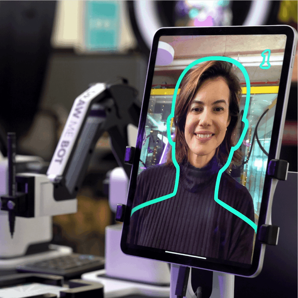 Robo Portraits photo tablet with a drawing robot behind it