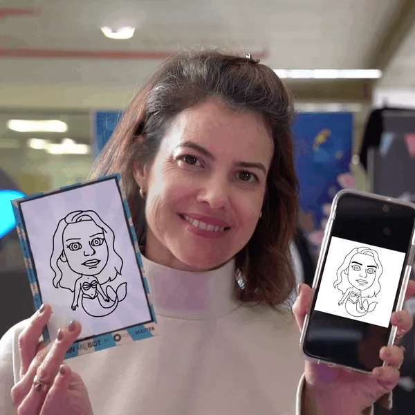 Woman holding up a pen-drawn caricature card and a phone showing the same drawing